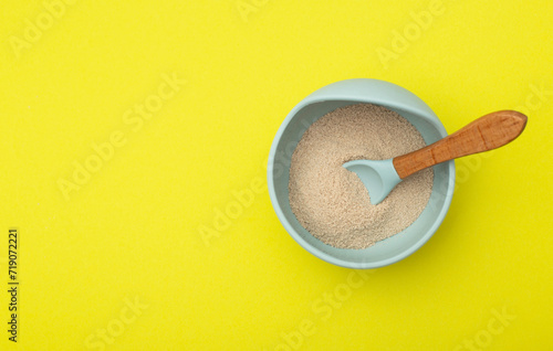Dairy-free vitamin buckwheat porridge in a plate on a yellow background. Baby food with minerals. Copy space for text  vegetable protein