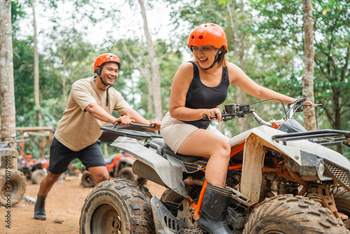young asian man pushing the atv that rided by the asian women at atv tracking area