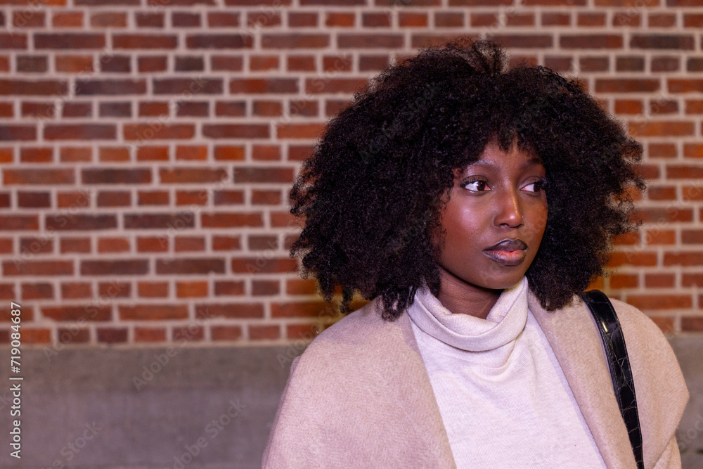 This image encapsulates a moment of introspection as a woman stands against the rich texture of a red brick wall. She appears to be caught in a moment of reverie, her profile to the camera, allowing This image encapsulates a moment of introspection as a woman stands against the rich texture of a red brick wall. She appears to be caught in a moment of reverie, her profile to the camera, allowing