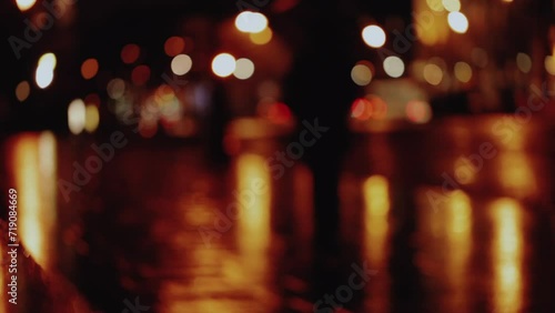 Wet city street with traffic lights refections at night in Paris