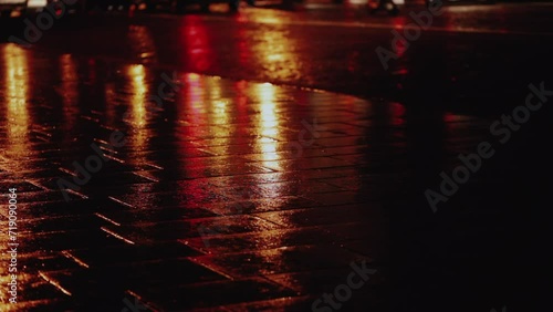 Wet city street with traffic lights refections at night in Paris