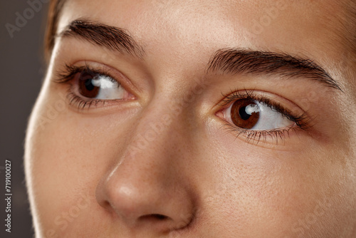 Fototapeta Naklejka Na Ścianę i Meble -  Close-up of female's brown eyes, nose, Model with no makeup. Health care, vision, pore cleansing. Concept of natural beauty, cosmetology and cosmetics, skin care