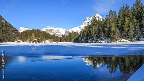 Panorama winter landscape of the frozen Arni Lake with the snow-convered Alps peak Windgaellen and its reflection photo