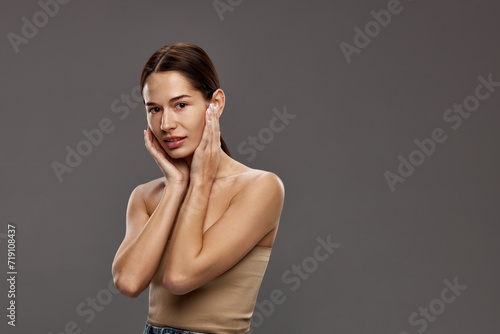 Portrait of beautiful young woman with spotless, well-kept, healthy sooth skin without makeup against studio background. Concept of natural beauty, cosmetology and cosmetics, skin care