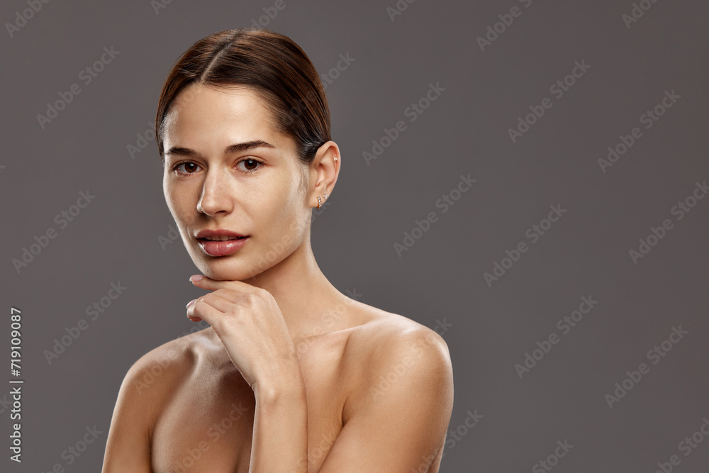 Portrait of beautiful young woman with bare shoulders, perfect smooth spotless face, well-kept skin against studio background. Concept of natural beauty, cosmetology and cosmetics, skin care Portrait of beautiful young woman with bare shoulders, perfect smooth spotless face, well-kept skin against studio background. Concept of natural beauty, cosmetology and cosmetics, skin care
