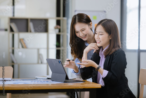 Happy two asian businesswoman working with tablet in meeting room, Businesswoman standing and talking about ideas in office workplace.