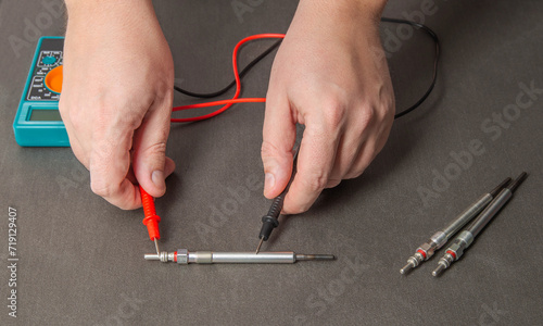 Checking the serviceability of the glow plug with a multimeter. Glow plug voltage resistance. Modern heating element, close-up