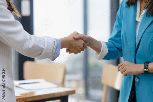 Happy two asian businesswoman making handshake with partner in meeting room, Businesswoman standing and talking about ideas in office workplace.