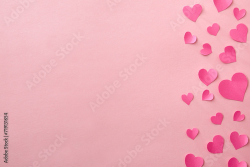 Love background with fuxia pink heart cutouts of various sizes on the right edge isolated on a pink background photo