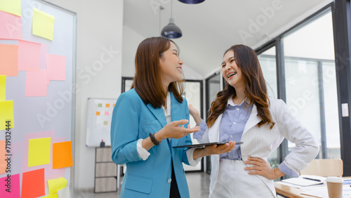 Happy two asian businesswoman working with tablet in meeting room, Businesswoman standing and talking about ideas in office workplace.