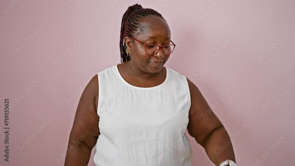 Shocked plus size african american woman casually standing, face expressing surprise as she looks at time on watch over isolated pink background Shocked plus size african american woman casually standing, face expressing surprise as she looks at time on watch over isolated pink background