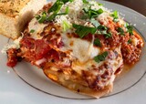 Baked lasagna layered with meat, ricotta and mozzarella cheeses, and tomato sauce on a plate in an Italian restaurant