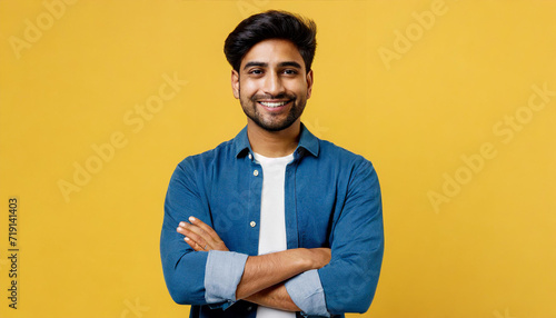 Young smiling happy cheerful Indian man he wearing shirt casual clothes look camera hold hands crossed folded look camera isolated on plain yellow color background studio portrait. Lifestyle concept photo