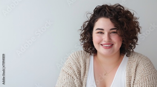 Positive reaction, attitude and life perception. Cute charming young Caucasian woman with curvy body posing at gray office wall and smiling cheerfully at camera, rejoicing at her career success photo