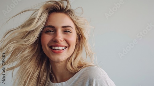 Happy blonde carefree woman with joyful expression, smiling while standing in relaxed pose against white background with cool hairstyle 