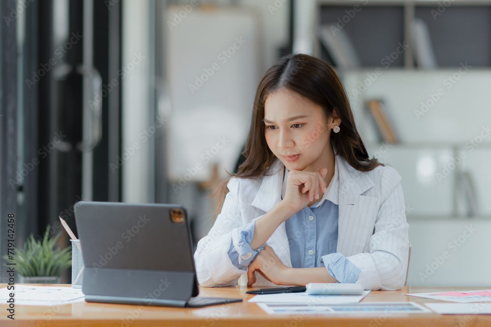 Asian businesswoman working on tablet with documents and stressed over worked from work in the office, Tired and Overworked businesswoman concept.