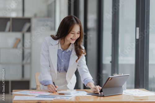 Asian Businesswoman working with tablet computer at office desk, Business accounting analysis report and financial concept.
