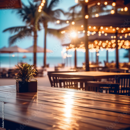 Wooden table and abstract blurred background of cafe with bokeh light. Wooden table with blur beach cafes background and bokeh lights created © Irina