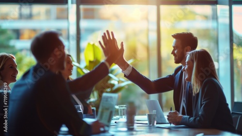 Successful business people giving each other a high five in a meeting. Two young business professionals celebrating teamwork in an office.