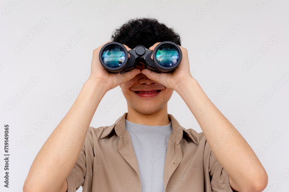 A cheerful young Asian man is using binoculars to explore, symbolizing curiosity, search, and discovery. A cheerful young Asian man is using binoculars to explore, symbolizing curiosity, search, and discovery.