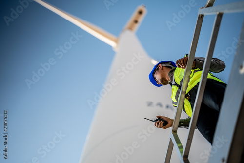 Asian engineers working in fieldwork outdoor. Workers check and inspect construction and machine around building project site. Wind turbine for electrical of clean energy and environment sustainable.
