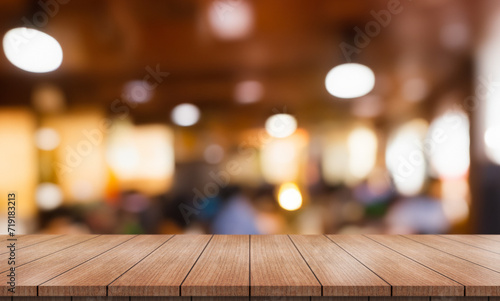 Empty wooden table top with lights bokeh on blur restaurant background.