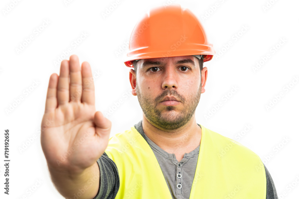 Builder man wearing safety hardhat making stop gesture with  palm