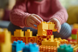 Close up of child hands playing with colorful building blocks. Preschool kid building tower with plastic blocks at home or kindergarten, daycare center or nursery