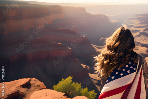 Obraz na płótnie Woman with an American flag on the edge of a canyon at sunset. US Independence Day. w salonie