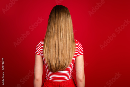 Photo of attractive slender girl wear striped top standing back showing long hair isolated red color background