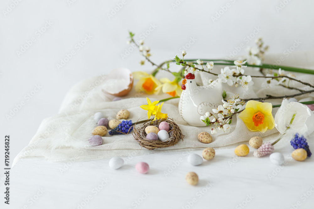 Happy Easter! Stylish easter chocolate eggs in nest, spring flowers, chicken figurine on white rustic wooden table. Easter modern simple banner, space for text. Seasons greetings Happy Easter! Stylish easter chocolate eggs in nest, spring flowers, chicken figurine on white rustic wooden table. Easter modern simple banner, space for text. Seasons greetings