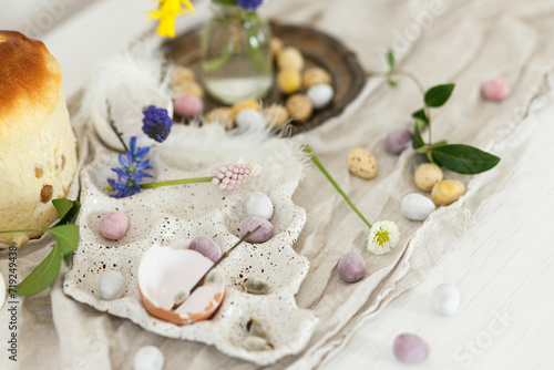 Fototapeta Naklejka Na Ścianę i Meble -  Colorful easter chocolate eggs, easter bread, spring flowers and linen cloth on rustic wooden table. Easter modern simple decoration and homemade traditional cake. Happy Easter!