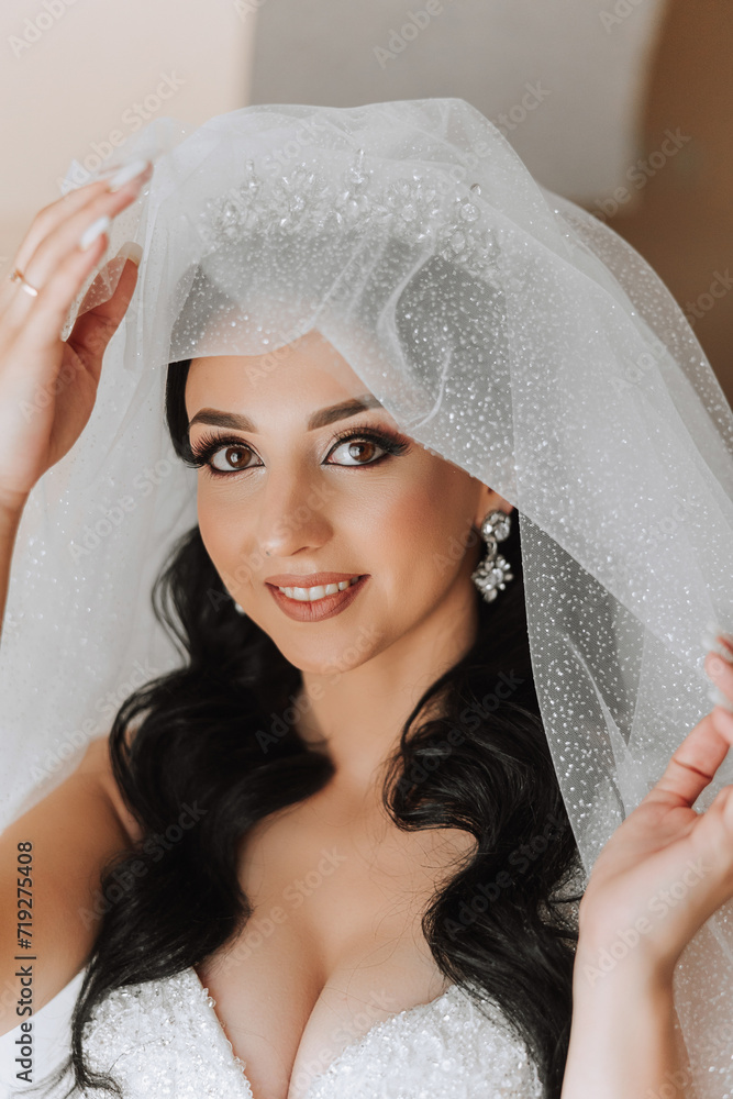 Fototapeta premium Portrait of the bride in the hotel room. A beautiful young girl is dressed in a white wedding dress. Modern wedding hairstyle. Natural makeup.