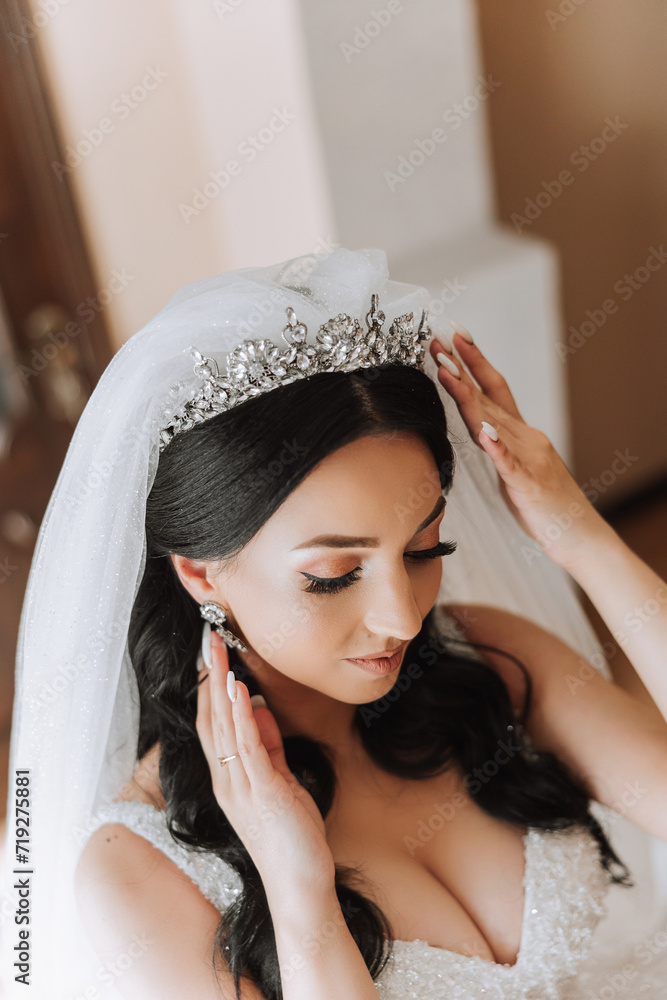 Fototapeta premium Portrait of the bride in the hotel room. A beautiful young girl is dressed in a white wedding dress. Modern wedding hairstyle. Natural makeup.