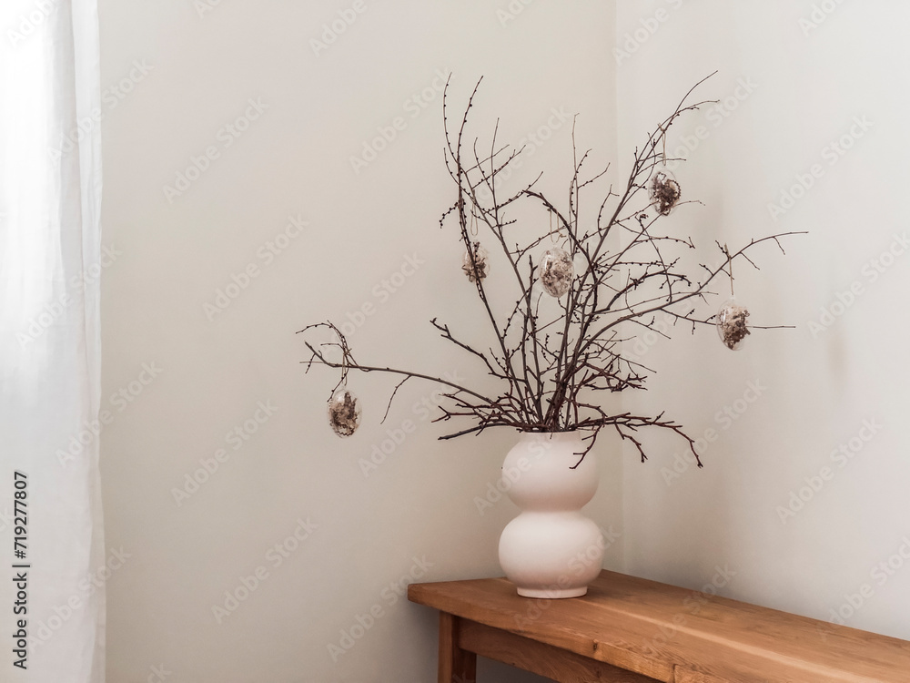 A simple homemade Easter bouquet made of dry twigs and glass Easter eggs on a wooden bench A simple homemade Easter bouquet made of dry twigs and glass Easter eggs on a wooden bench