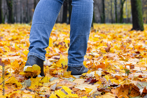woman walking through autumn leaves in the park.