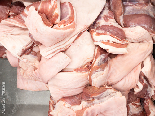 The raw pork belly in the metal tray for sale.