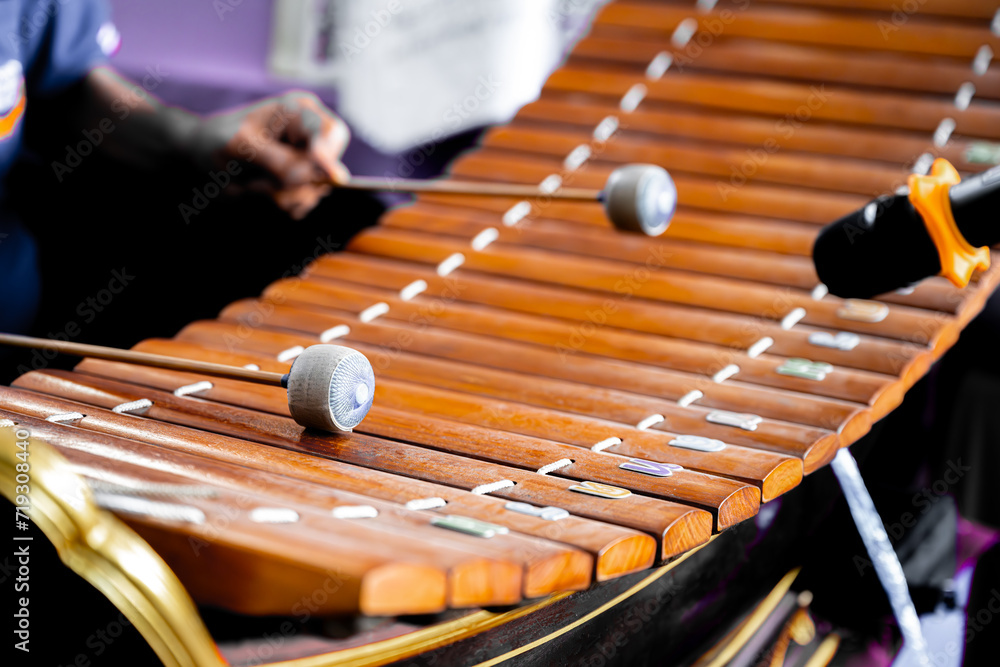 Thai Xylophone 'Ranat' in Musical Performance. An artist's hands playing a traditional Thai xylophone, called a Ranat, with fabric mallets, during a cultural musical performance.