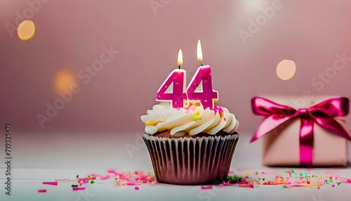 Birthday cupcake with burning lit candle with number 44. Number fortyfour for fortyfour years or fortyfourth anniversary. photo