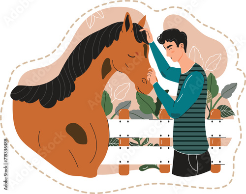 Young man bonding with horse, petting its forehead in a stable setting. Animal lover showing affection to a brown horse near white fence.