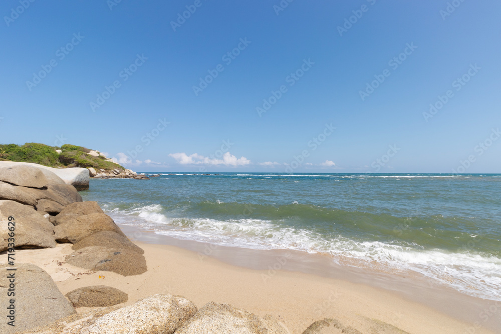 Colombian caribbean lonely beach with big rocks and tropical jungle mountains in sunny day landscape