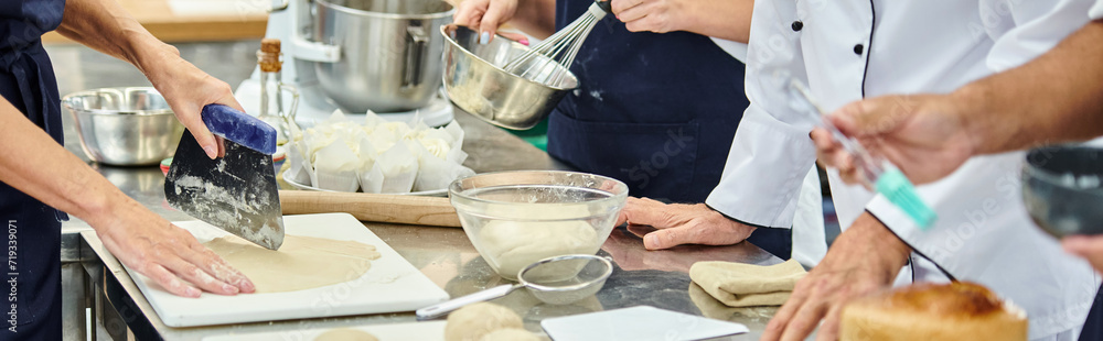 cropped view of hard working chefs in aprons working with dough on kitchen, confectionery, banner cropped view of hard working chefs in aprons working with dough on kitchen, confectionery, banner