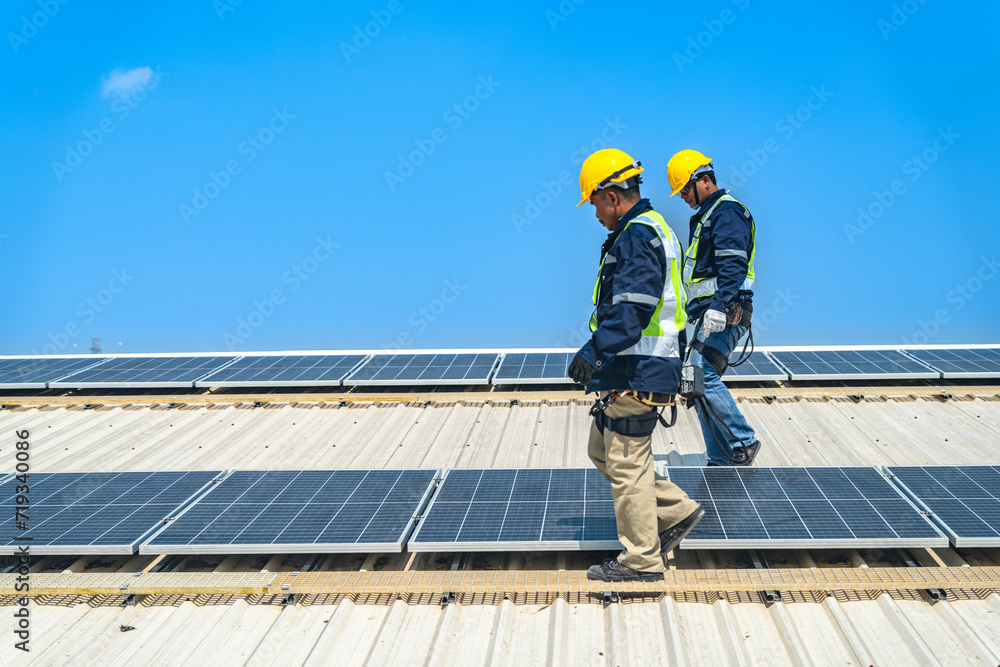 Fototapeta premium Worker Technicians are working to construct solar panels system on roof with sky and clound on background. Installing solar photovoltaic panel system. Renewable clean energy technology concept.