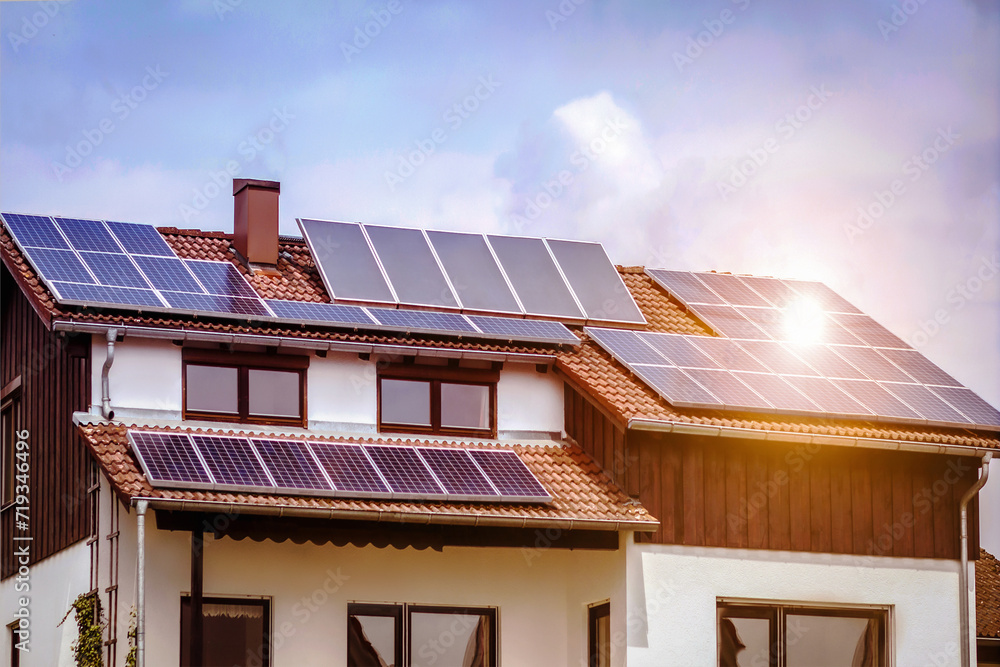 Fototapeta premium Solar Panels on Roof of Alpine House with White Facade with Sun Reflection. Photovoltaic Panels on Roof House.