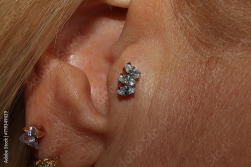 Girl ear piercing. Macro. Tragus piercing + titanium labret with triple marquise cubic zirconia. 