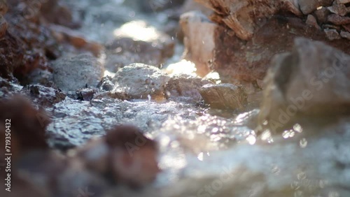 Close-up video of the purest transparent water in a mountain river flowing among the stones. Details of a sunny day in the mountains. Pure still clean water in a mountain spring photo