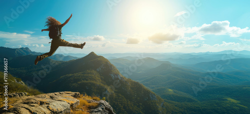 Concepto persona saltando libre en un campo a plena luz del día de tare con montañas de fondo. © Anta