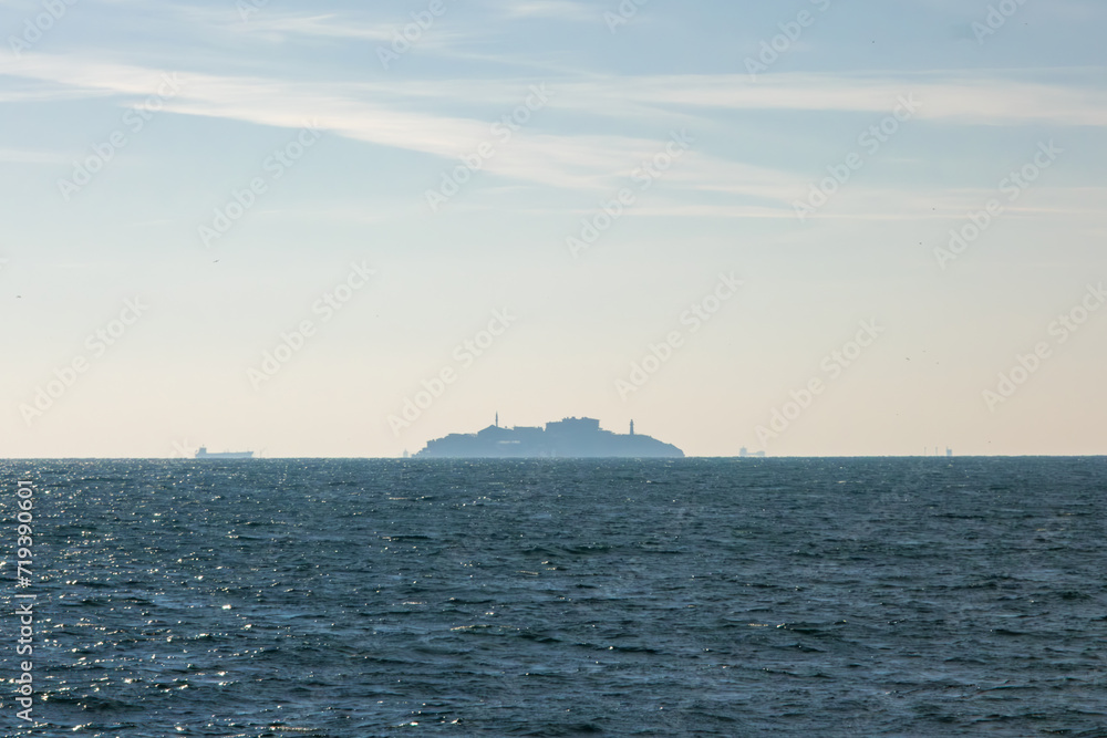An island and ships visible on the horizon in the sea