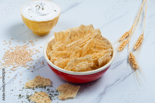 Red enameled bowl filled with tarhana chips, Turkish snack made with flour, wheat berries, mint, yogurt and spices also known as frik photo