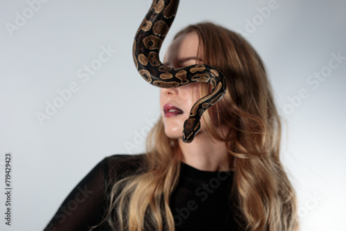 young blond woman with black dress and real snake python 